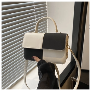 Detail of a black and white color-block crossbody bag with gold-tone metal hardware