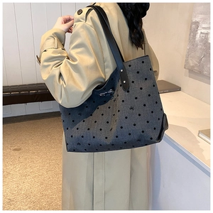 Detailed view of dark grey canvas tote with polka dots and bow embroidery on a model