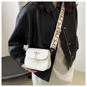 Detailed view of white saddle crossbody bag featuring a deer charm and patterned strap