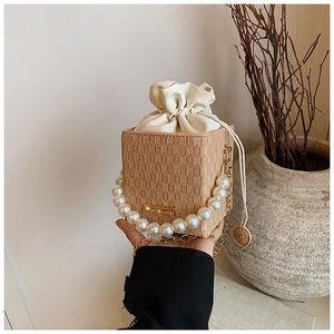 Détail du sac seau beige à carreaux avec poignée en perles et cordon de serrage
