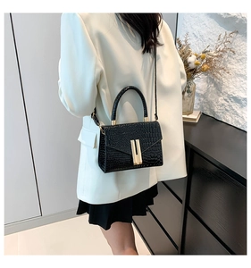 Detail of black crocodile embossed small square bag with elegant golden metal clasp