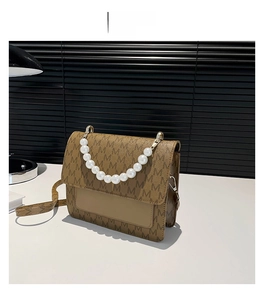 Detail view of brown crossbody bag with letter print patterns and luxury pearl handle