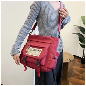 Dettaglio della borsa a tracolla in nylon bordeaux con spallacci regolabili e fibbia a scatto