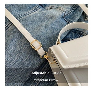 Detailed close-up of white leather bag featuring adjustable buckle and neat stitching