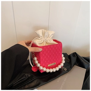 Dettaglio mini borsa a secchiello intrecciata rosa con manico di perle e coulisse