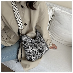 Detail of checkered tote bag with wide shoulder strap and black and white geometric pattern