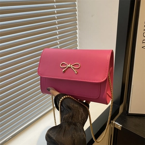Hot pink rectangular leather underarm bag featuring a gold metal bow and chain strap