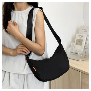 Detailed side view of black dumpling crossbody bag with orange label on minimalist model