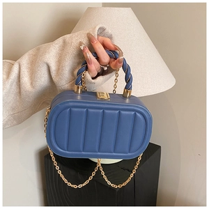 Detail of blue pill-shaped box bag with vertical ribbing and gold chain strap