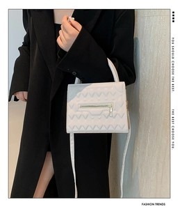 Detail of white PU leather crossbody bag with V-shaped quilted texture and top handle