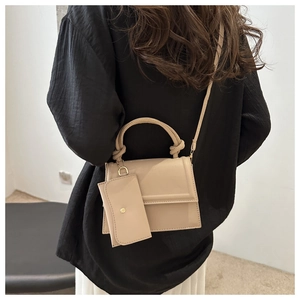 Minimalist beige crossbody bag shown on model with matching coin purse and top handle