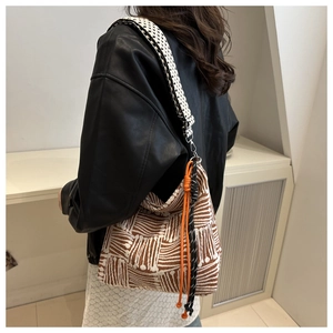 Detail of canvas tote featuring geometric patterns and a checkered wide shoulder strap