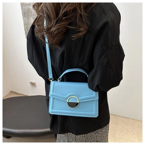Detail of sky blue crossbody bag with gold half-circle buckle shown on a model
