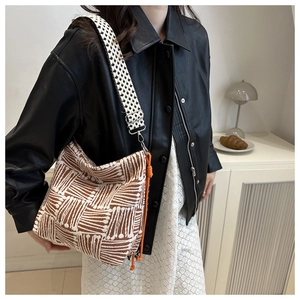Detail of checkered tote bag with orange rope drawstring and wide patterned shoulder strap