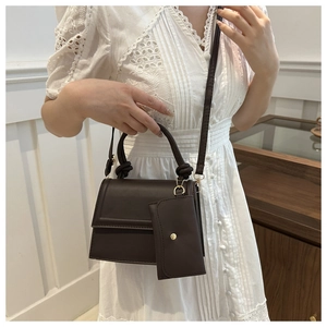 Detail of dark brown matte leather crossbody bag with knot handle and mini coin purse