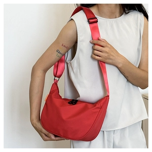 Side view of red nylon crescent crossbody bag with adjustable wide shoulder strap on model