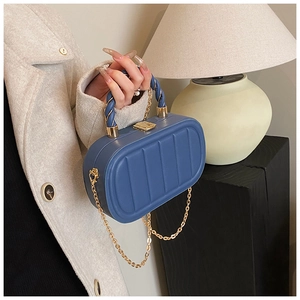 Detail of navy blue vertical quilted evening bag with gold chain and rope handle