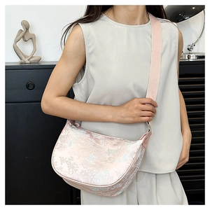 Detail of pink jacquard crescent bag with blue landscape pattern and wide fabric strap