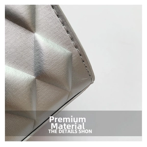 Macro shot of quilted faux leather texture and precise stitching on light grey handbag