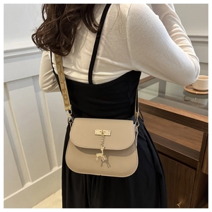 Détail du sac beige avec pendentif cerf doré et bandoulière en jacquard élégante