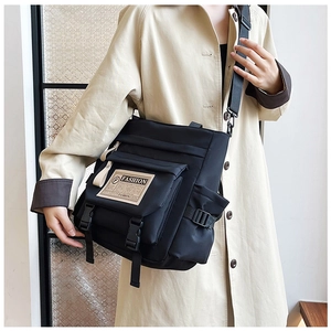 Dettaglio della borsa a tracolla in nylon nero con fibbie e toppa decorativa moda