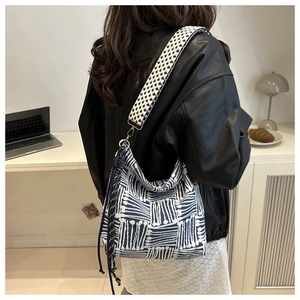 Detail of blue and white geometric canvas tote with checkered strap and tassel accents