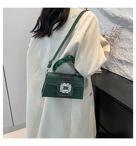 Detail of green crocodile embossed bag featuring a sparkling crystal square buckle