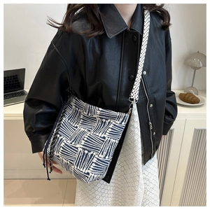 Detail of striped canvas bucket bag showing navy blue geometric texture and tassel details