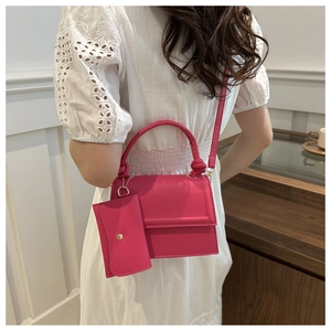 Detail of fuchsia crossbody bag with woven handle and matching mini pouch accessory