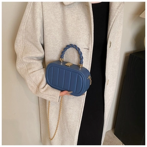 Blue box bag detail featuring vertical ribbed texture, woven handle and gold chain strap