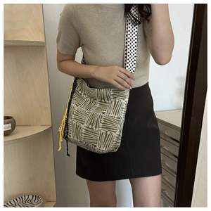 Detail of green and white woven tote bag featuring a yellow drawstring and patterned strap