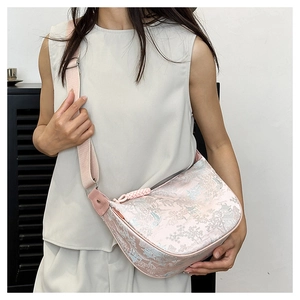 Detailed side view of a pink embroidered crossbody bag with traditional Chinese patterns