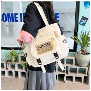 Dettaglio di una grande borsa a tracolla in nylon crema con etichetta moda e tasca laterale