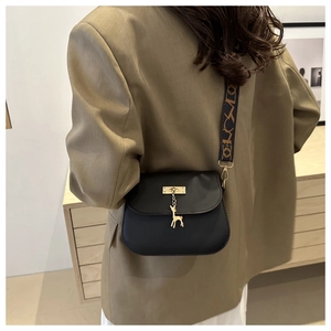Détail du sac bandoulière noir avec pendentif cerf doré et sangle à motifs géométriques