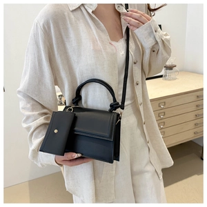 Détail du sac à bandoulière noir minimaliste avec poignée nouée et petit porte-monnaie