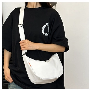 Detail of white half-moon crossbody bag with wide strap and orange side label