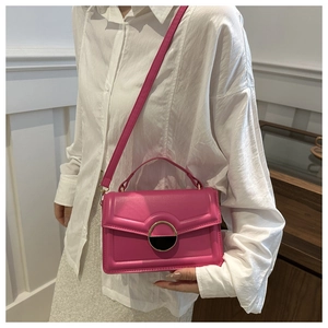 Model wearing a retro magenta crossbody bag with gold-tone buckle and flap design