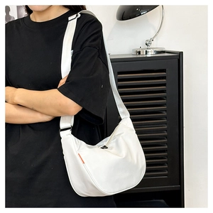 Detail view of the white nylon crescent bag with adjustable wide strap and orange label