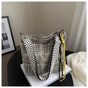 Detail of olive green jacquard tote with star pattern strap and woven tassel charm