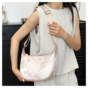 Detailed texture of pink jacquard fabric with elegant floral and building patterns on a hobo bag