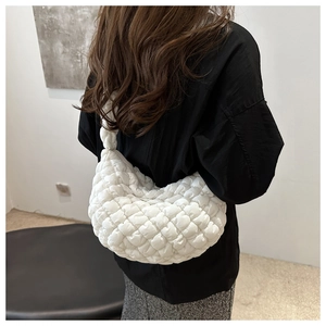 Vue de profil d'un sac à bandoulière matelassé blanc porté avec un style minimaliste