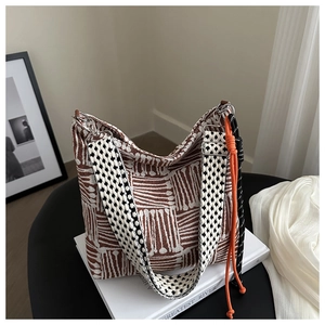 Detailed texture of brown and white striped knit bag with checkerboard strap on books