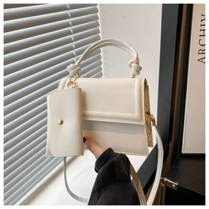 Gros plan d'un sac à main blanc minimaliste avec poignée nouée et cuir texturé granuleux