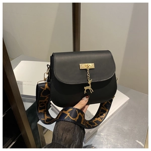 Détail du sac de selle noir mat avec pendentif cerf et bandoulière jacquard