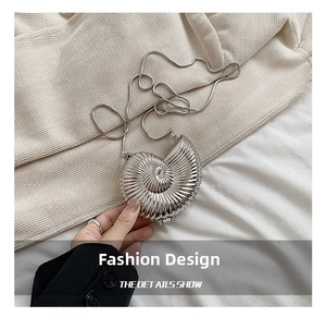 Close-up of a silver shell-shaped metal clutch bag with detailed 3D shell texture and chain
