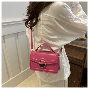 Detail view of a rose pink rectangular crossbody bag with gold-tone geometric metal clasp