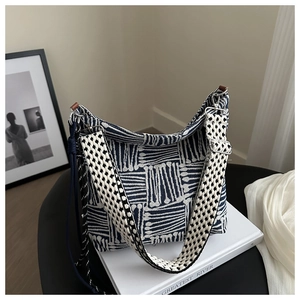 Detail of blue geometric tote bag with wide checkered shoulder strap and metal buckle