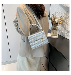 Detail of silver geometric embossed square bag with 3D diamond pattern and gold zipper