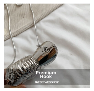 Detail of silver shell-shaped clutch with metal hook and elegant snake chain strap