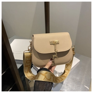 Détail du sac beige avec pendentif cerf doré et large bandoulière tissée à motifs